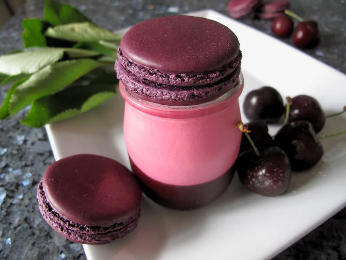 rose pink panna cotta dessert shot with cherry sauce and macarons