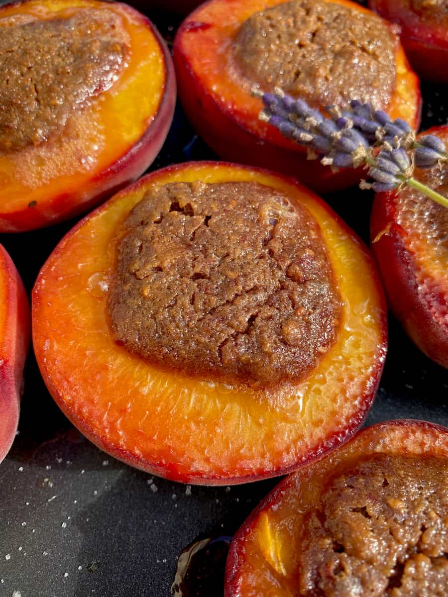 close up of a few baked peaches just out of the oven, stuffed with a toasted almond filling