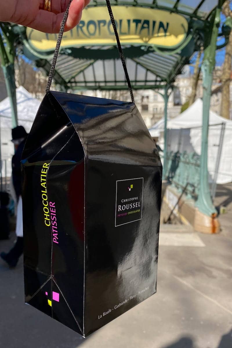 black shiny chocolate bag in front of the Paris metro