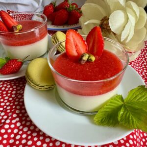 glass dessert dish of creamy pistachio panna cotta topped with a strawberry coulis