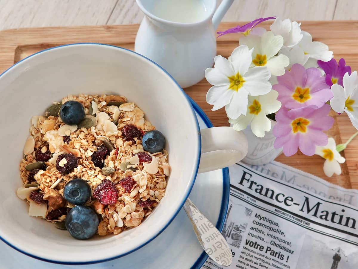 bowl of granola with fresh blueberries and French newspaper
