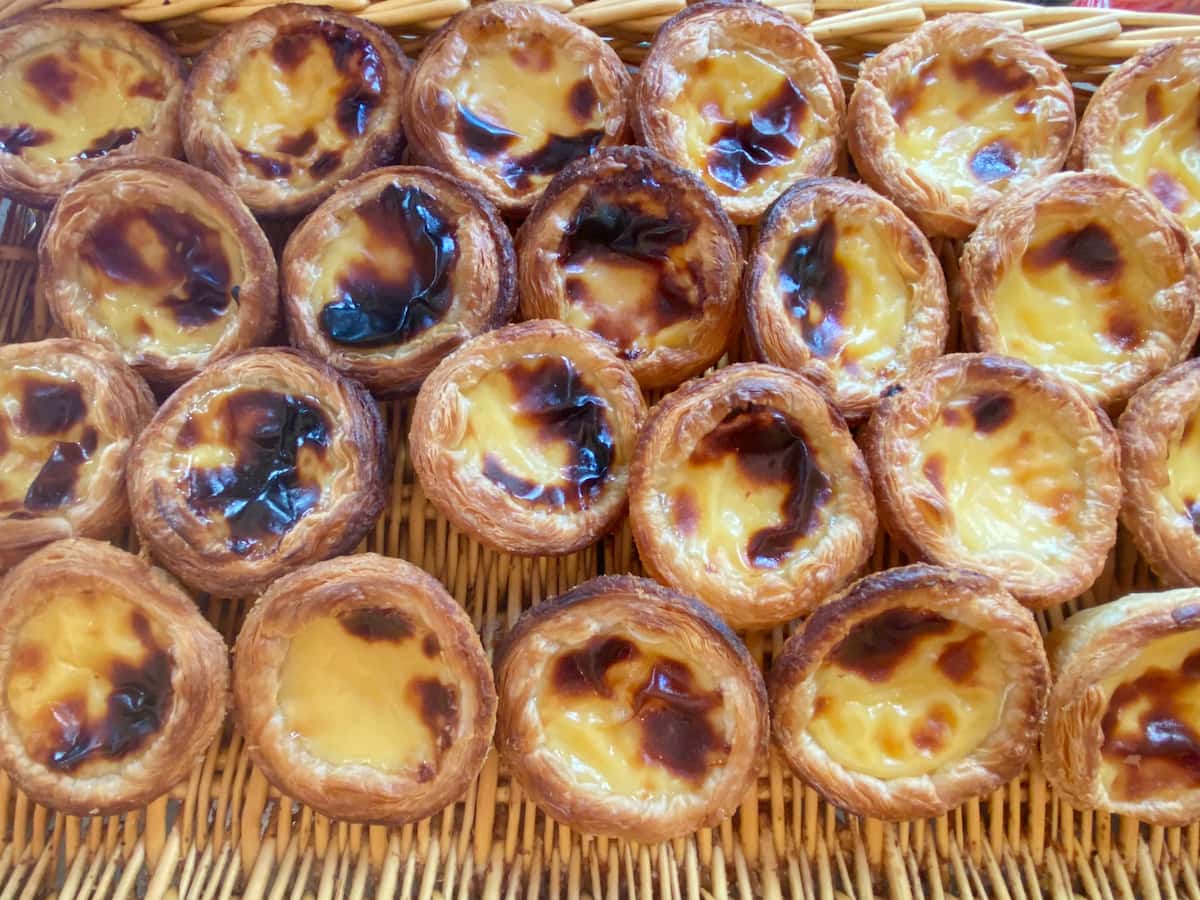 rows of freshly baked custard tarts in a wicker basket