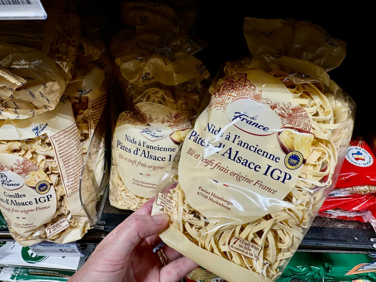 holding a packet of dried pasta with noodles in a French supermarket labelled from Alsace