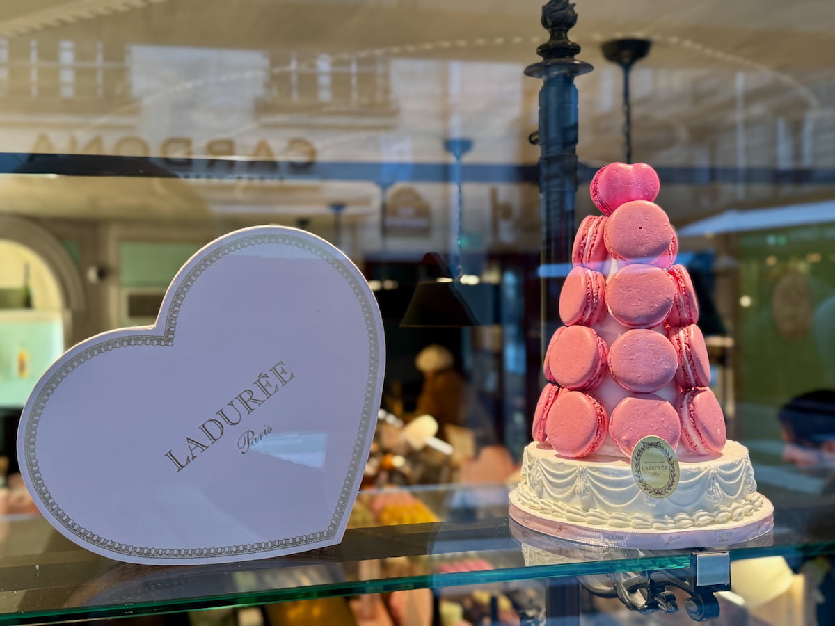 rose pink macaron tower in the window of laduree Paris with a heart shaped box