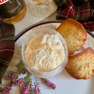 Whisky glass filled with soft scoop creamy ice cream next to almond cookies, heather and Whisky liqueur