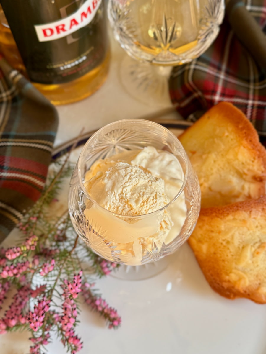 Whisky glass containing creamy soft ice cream with a bottle of Drambuie liqueur and tuile almond cookies