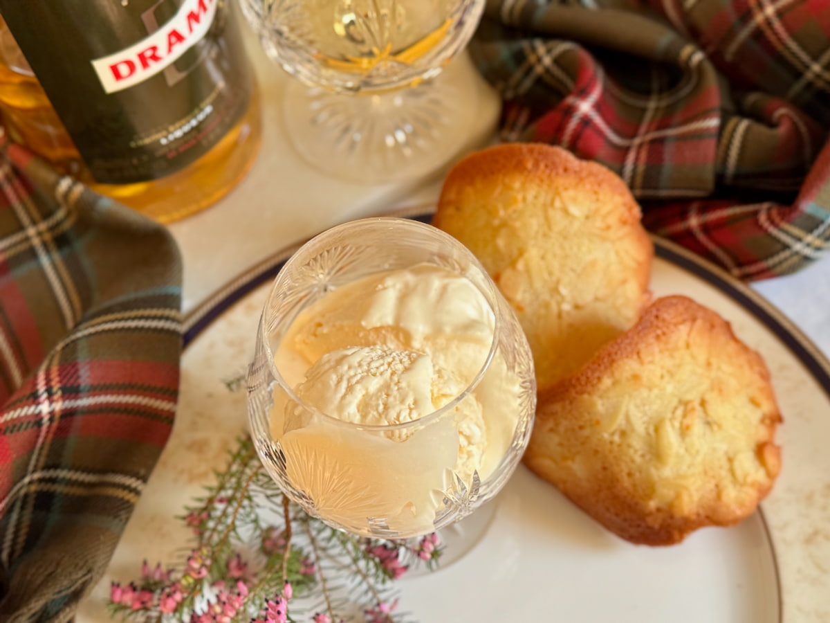 glass of soft scoop homemade ice cream made with alcohol next to crispy French almond cookies