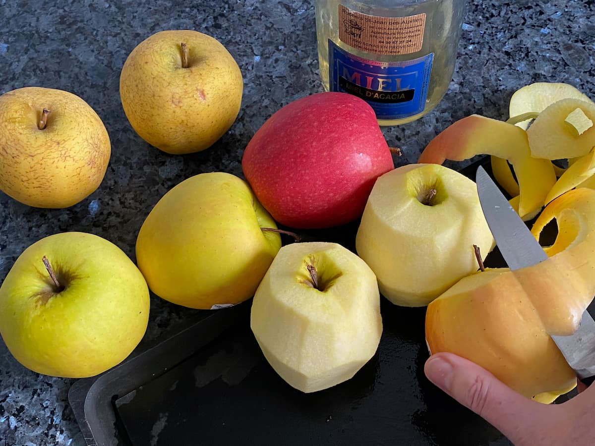 peeling and coring apples next to a big pot of honey