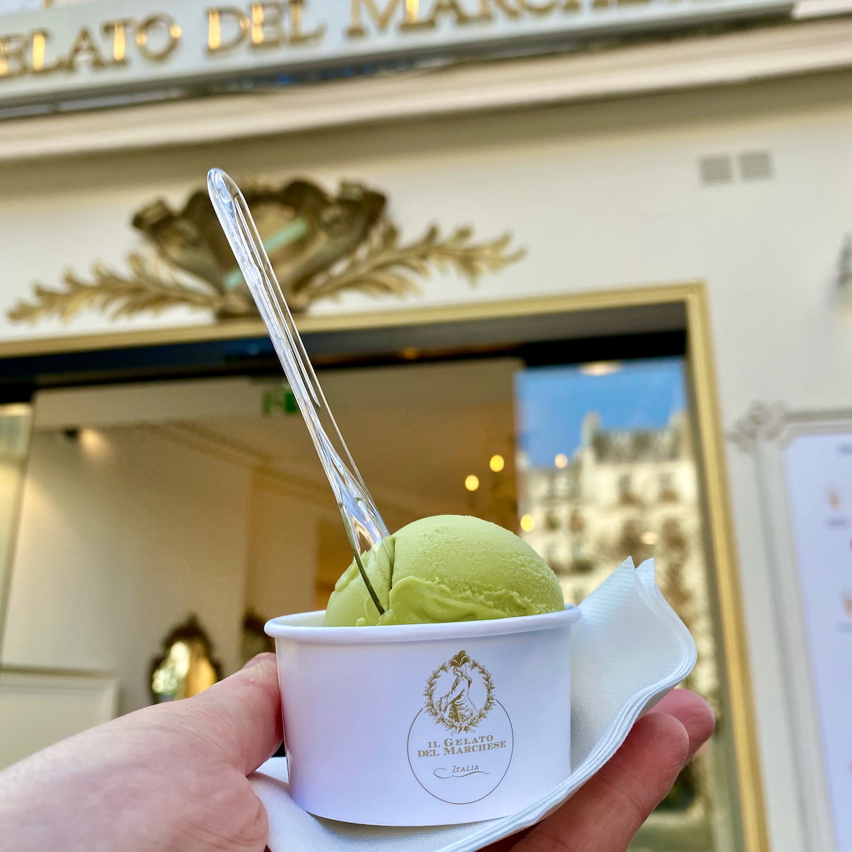 scoop of green tea ice cream in a cup in front of an Italian gelato shop in Paris
