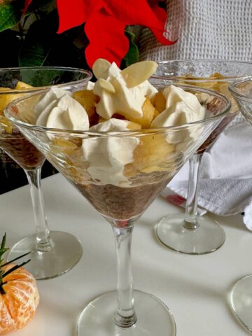 glass with a layered gingerbread trifle with caramelised apples, jelly, caramel and topped with boozy whipped cream