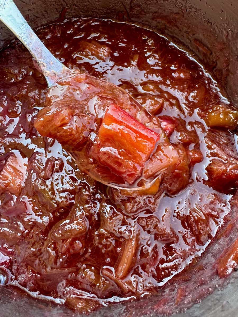 spoon of hot rhubarb jam in the pot, showing it has thickened