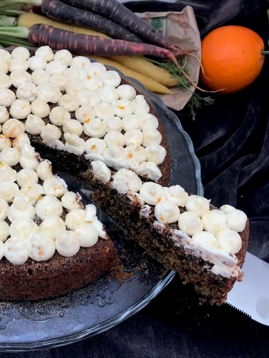 slice of purple carrot cake topped with creamy orange frosting