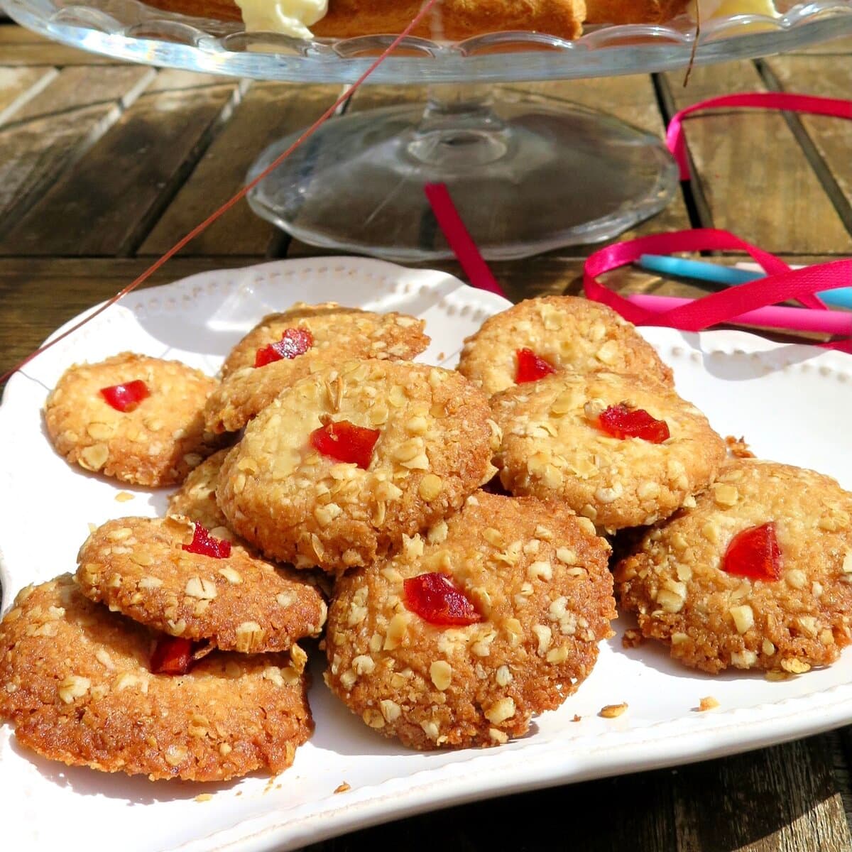 oat biscuits topped with glace cherries on white plate and birthday candles