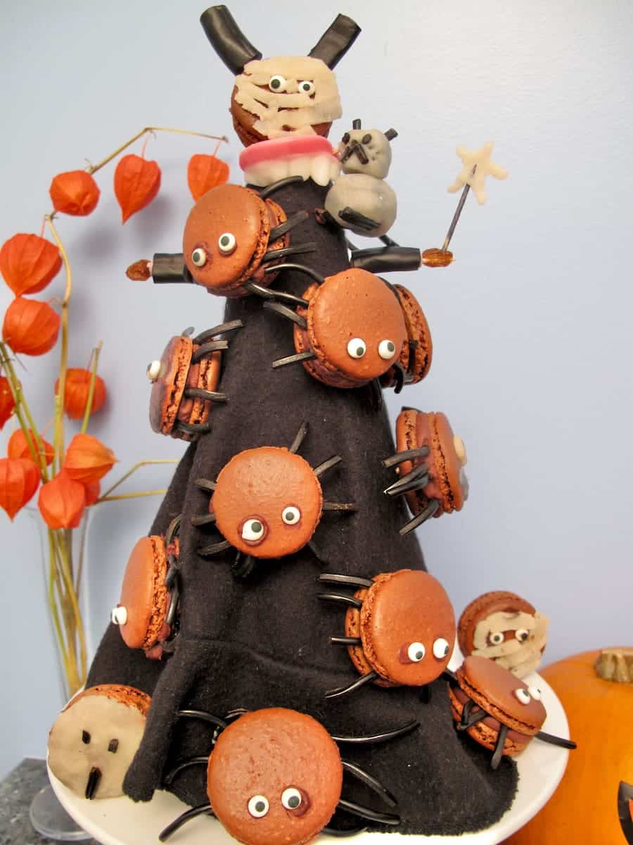 witch's black hat holding chocolate halloween macarons with eyes and spiders' legs