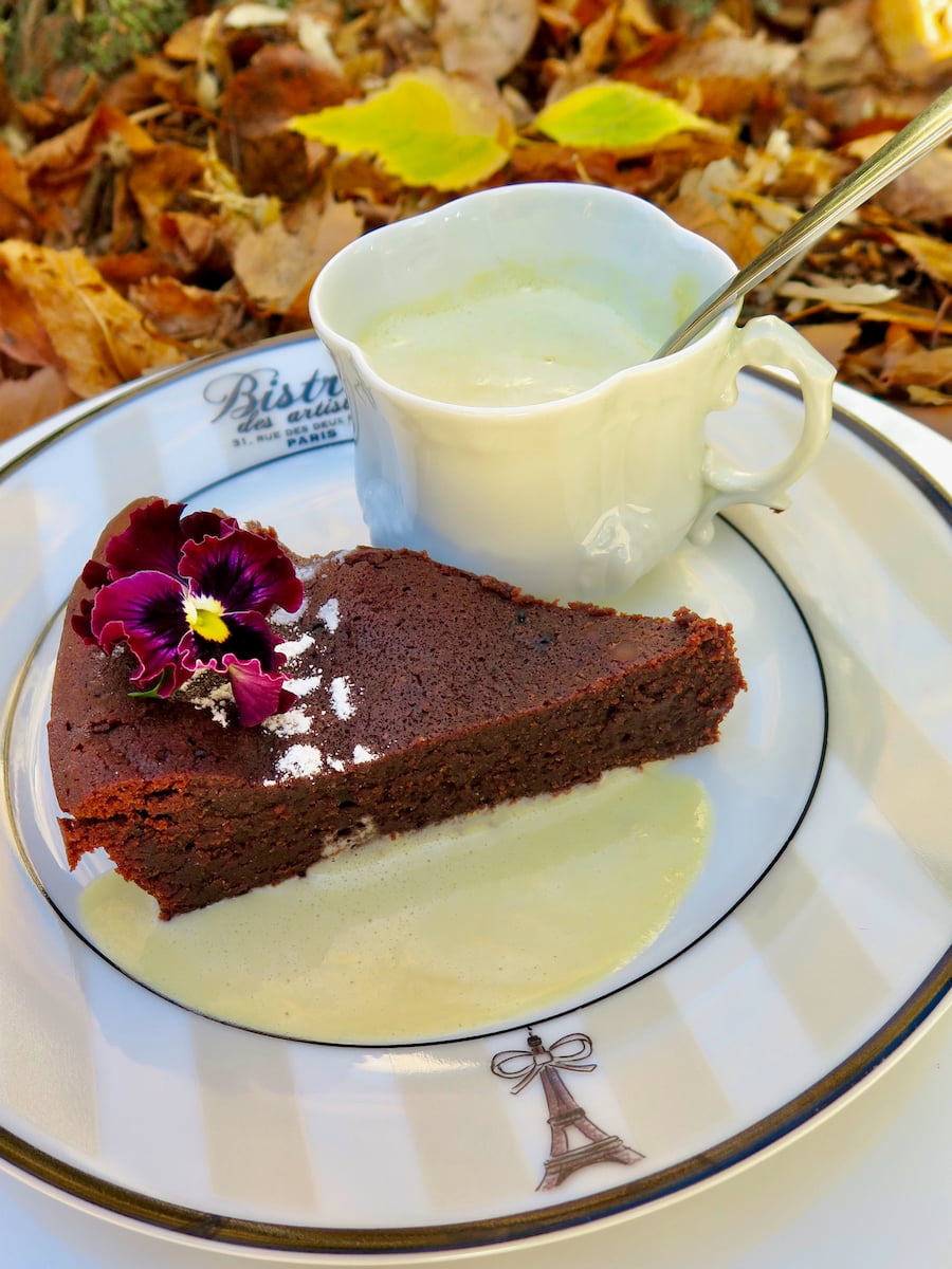 slice of fudgy chocolate cake surrounded in a pool of crème anglaise French custard sauce