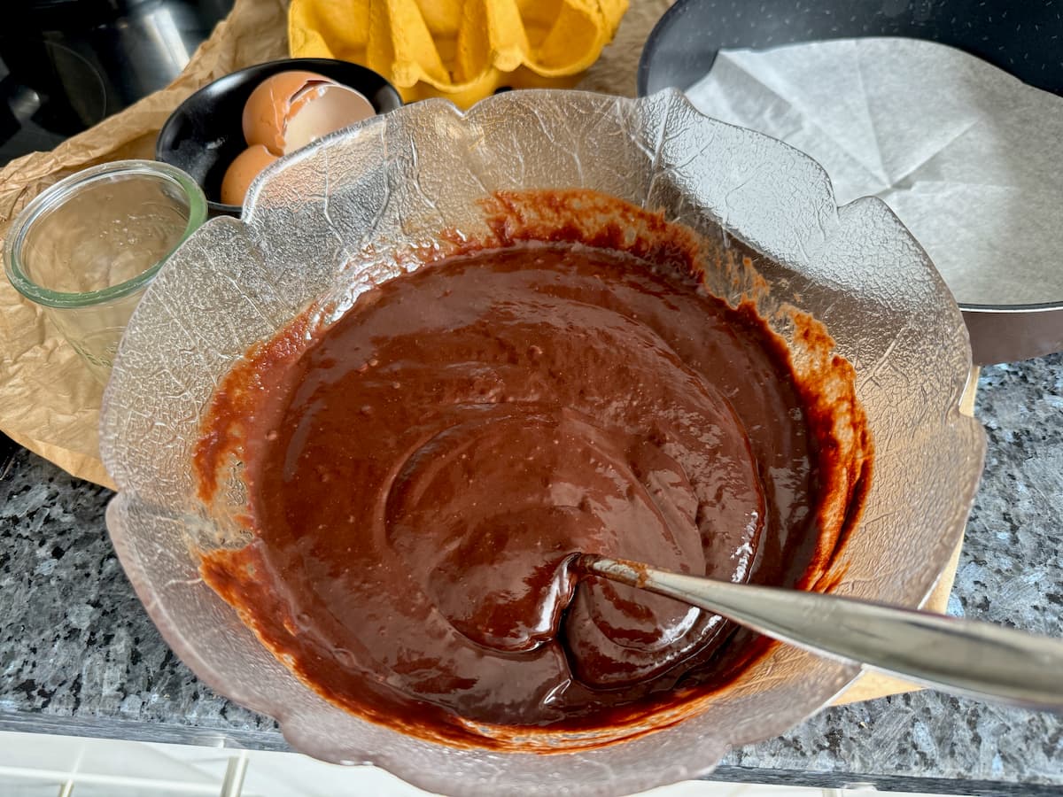 stirring a heatproof bowl of melted chocolate and butter with eggs and sugar.