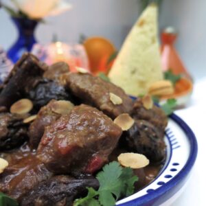 chicken tagine with prunes, toasted almonds and cone of semolina in background