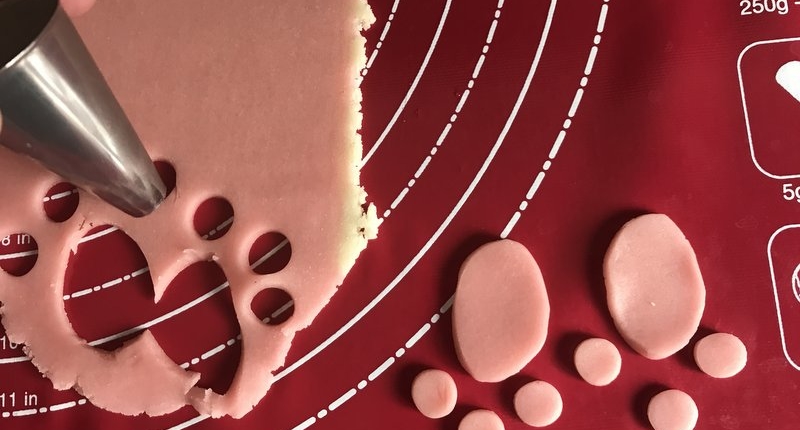 cutting out pink marzipan circles with a piping tip to make cake paws