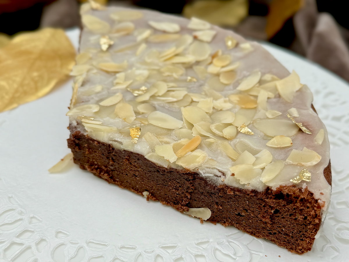 a one-layered chocolate almond cake topped with a rum glaze and toasted flaked almonds