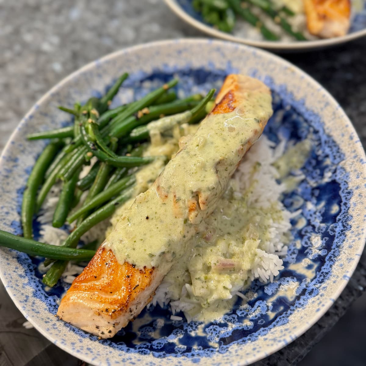 presentation dish of pan-fried salmon on a bed of rice, sautéed green beans and topped with a smooth beurre blanc sauce with added watercress