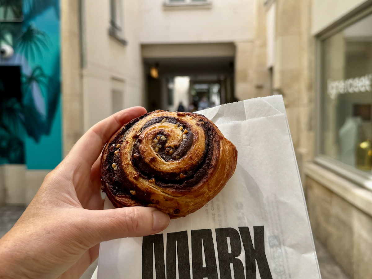 holding a chocolate hazelnut round escargot pastry by Thierry Marx