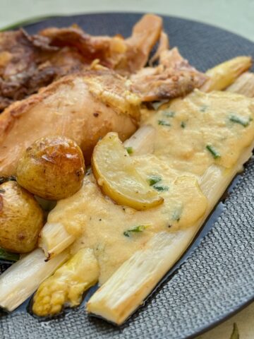 creamy lemon sauce poured over roasted white asparagus, served with potatoes and roast chicken