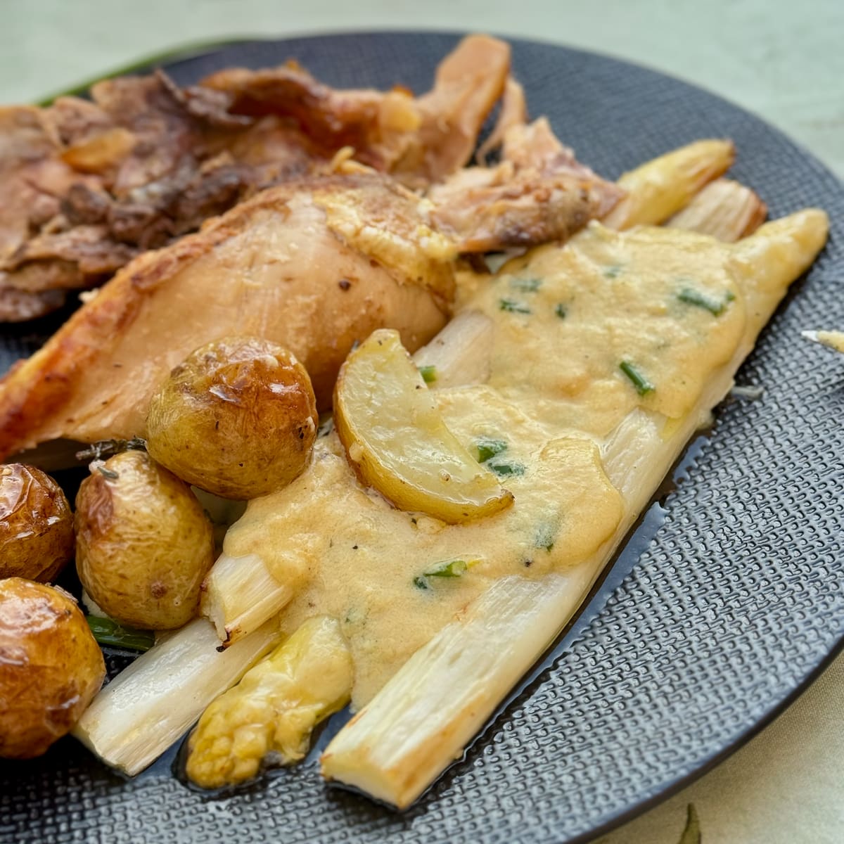 creamy lemon sauce poured over roasted white asparagus, served with potatoes and roast chicken