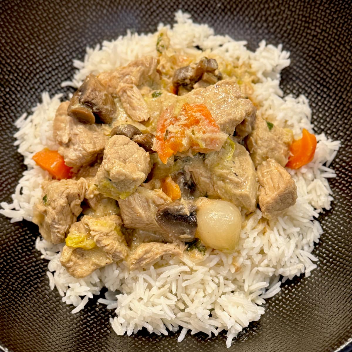 plate of a French creamy blanquette de veal veal stew with carrots, mushrooms and pearl onions on a bed of rice