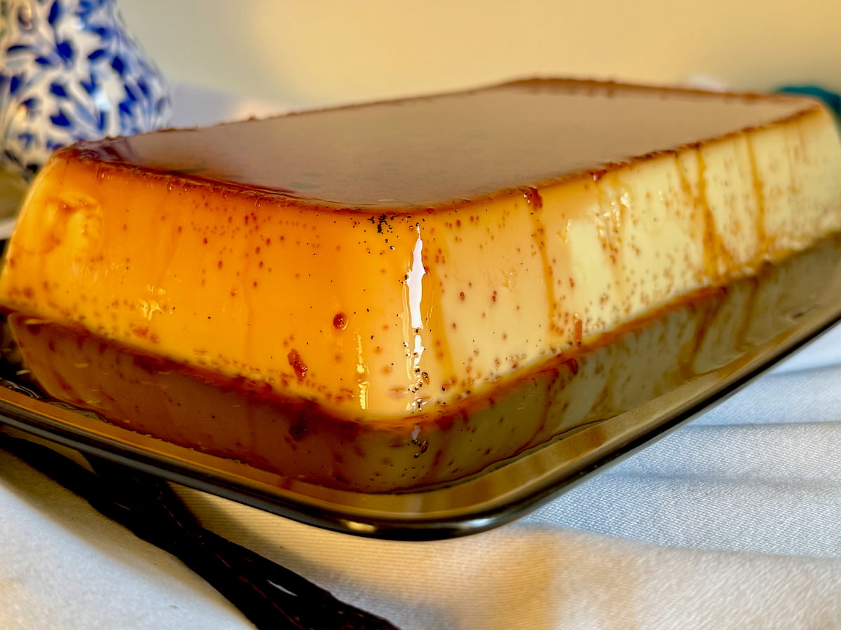 large creme caramel pudding on a big plate filled with shiny caramel sauce