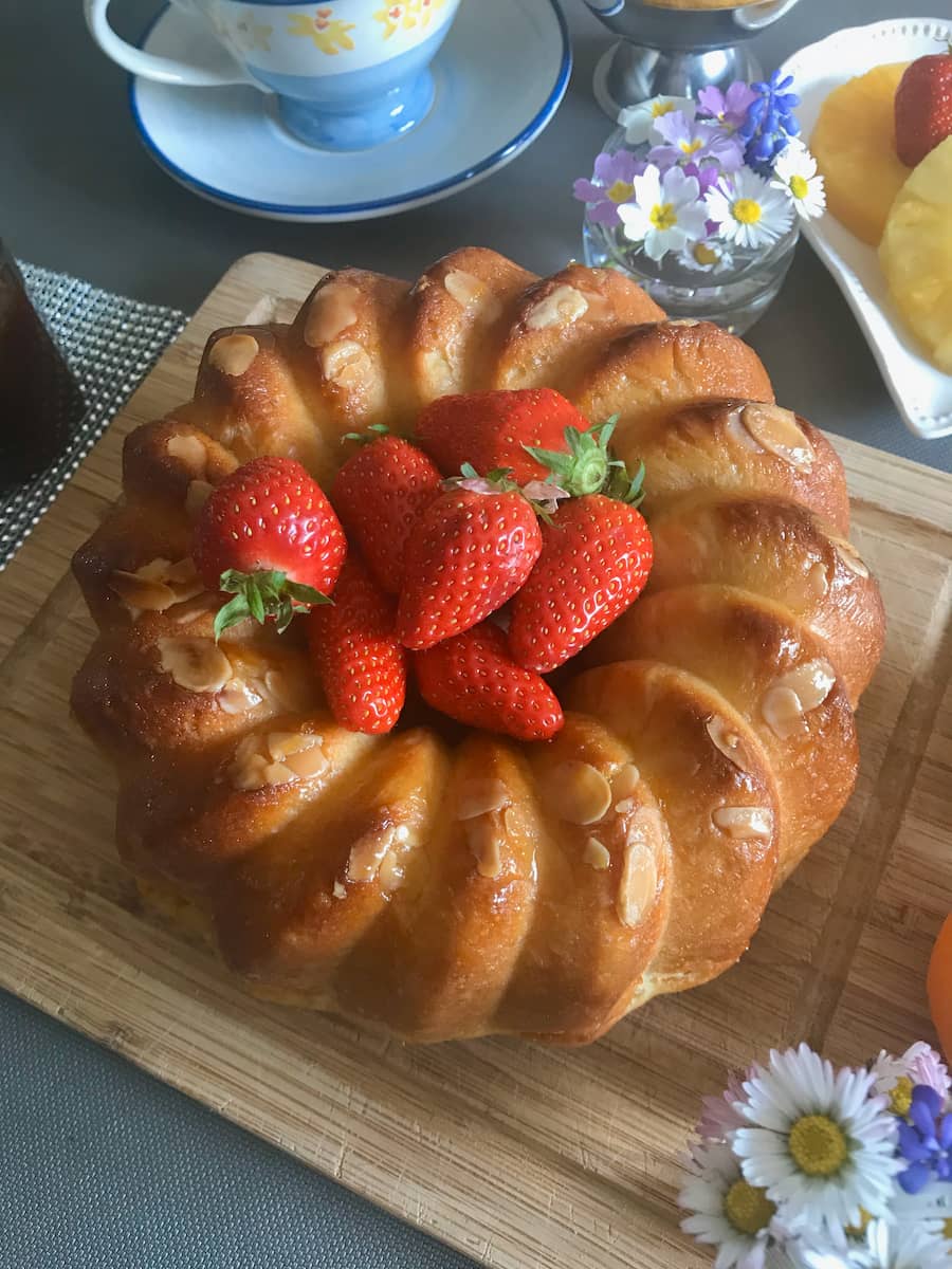 French brioche glazed and shaped in a ring with a pile of fresh strawberries in the middle