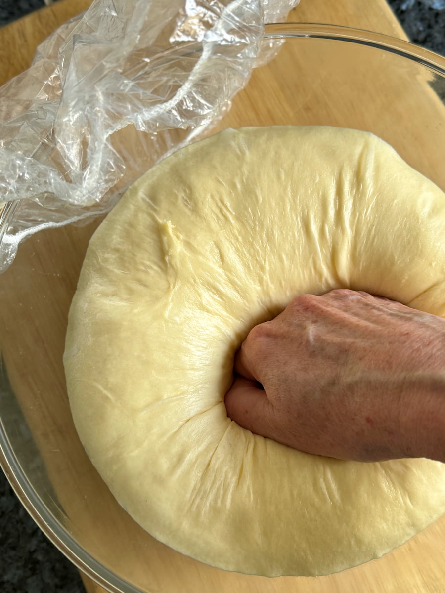 punching down risen brioche dough to knock out the yeast gases
