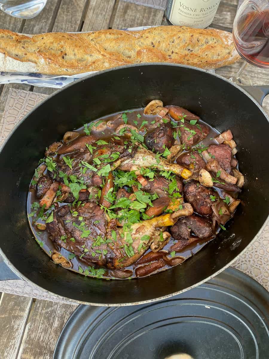 pot of coq au vin French chicken dish with red wine and baguette