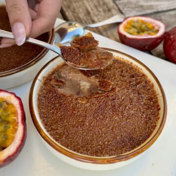 cracking in to a milk chocolate crème brûlée showing a delicious set custard topped with a thin caramelised crust - served with halved passionfruits