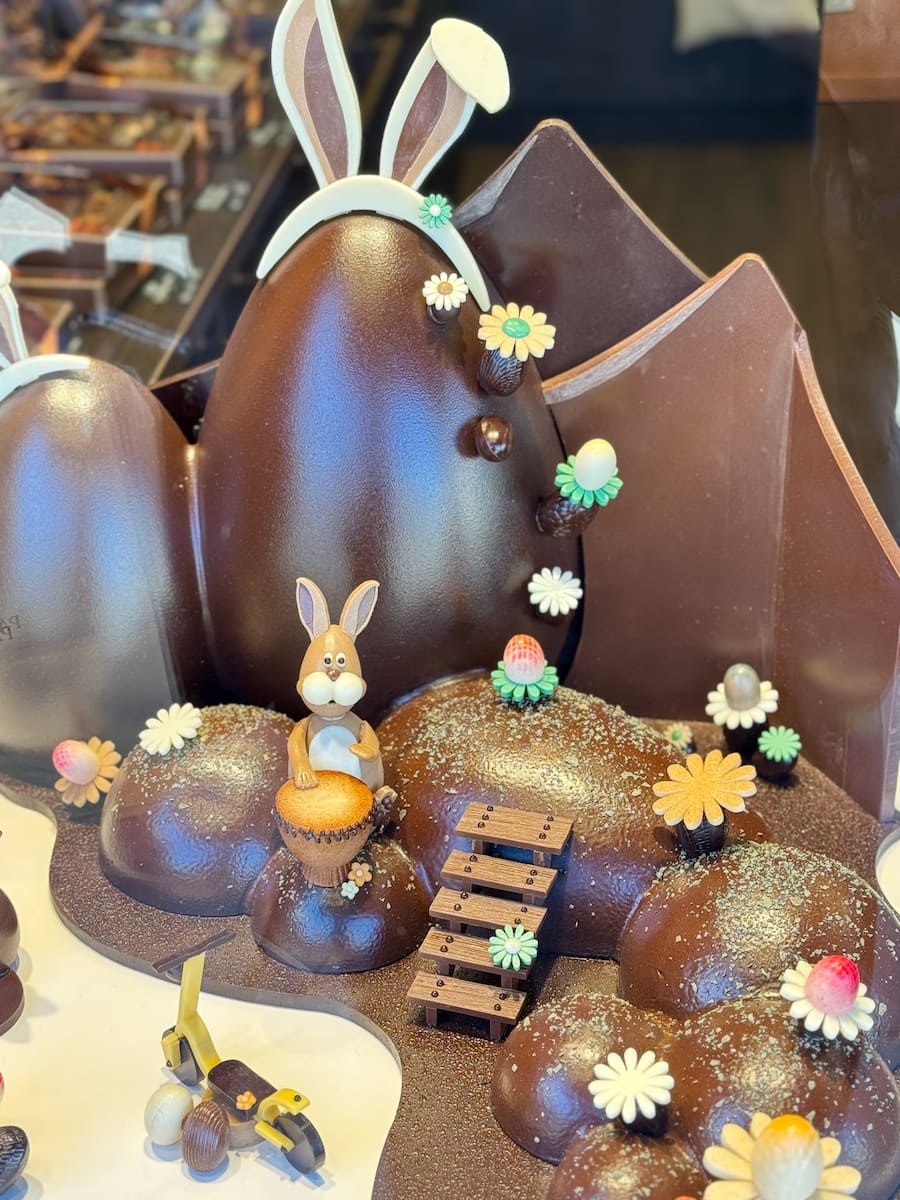 chocolate shop window in Paris of a giant easter egg with bunnies and a cute garden scene
