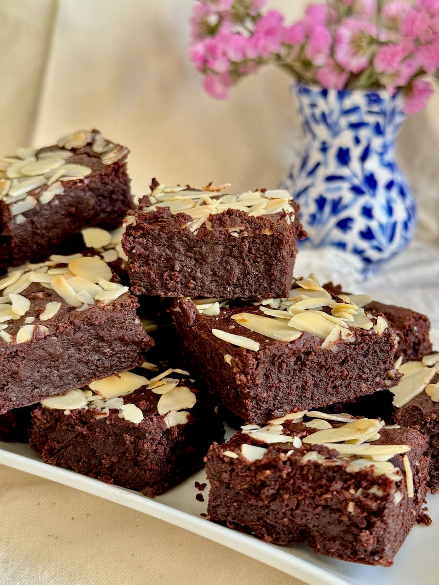 plate of the fudgiest brownies topped with almonds and made with almond flour