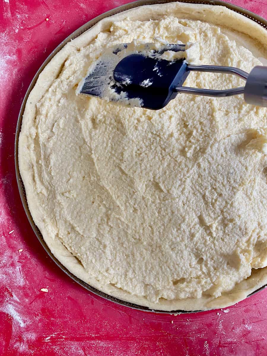 spreading almond cream over the surface of a tart shell to make a French almond cake with rum