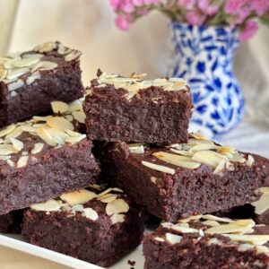 plate of gooey gluten free brownies made with almond flour and melted chocolate, topped with almonds