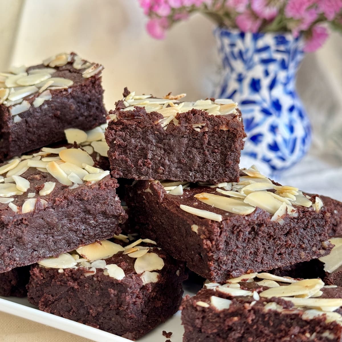 plate of gooey gluten free brownies made with almond flour and melted chocolate, topped with  almonds