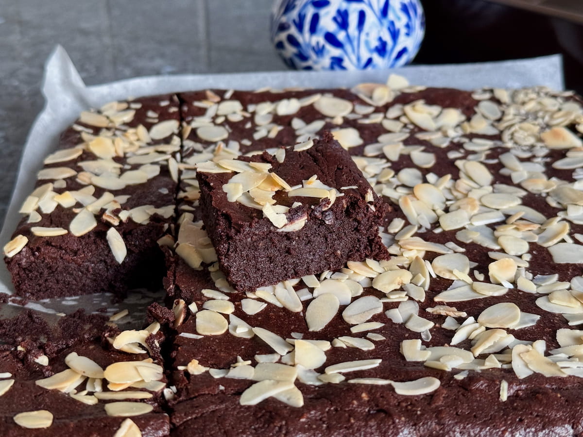 cutting squares of gooey gluten free brownies directly from the tin when cool, topped with slivered almonds