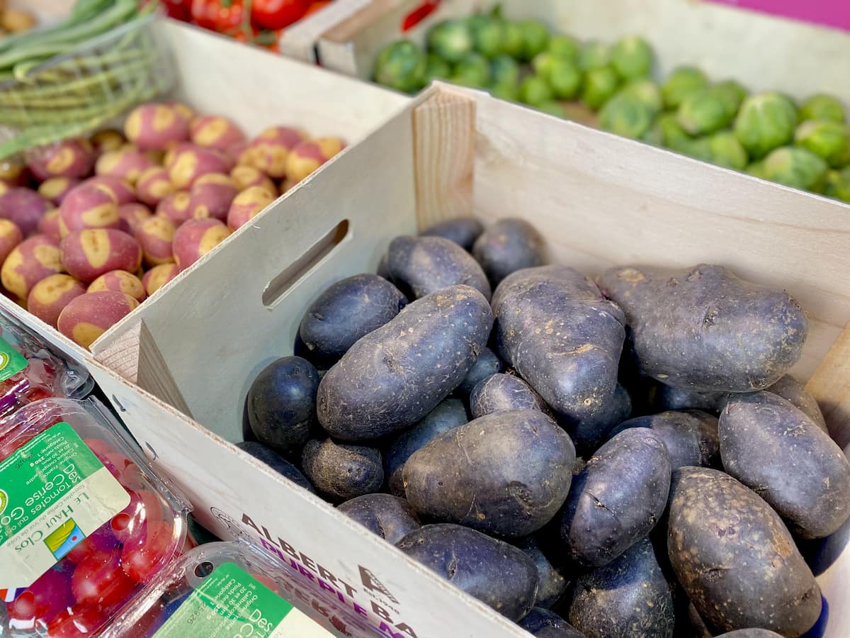 crate of large dark purple potatoes