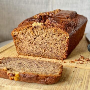 sliced banana coffee cake, showing a beautifully moist crumb and topped with walnuts