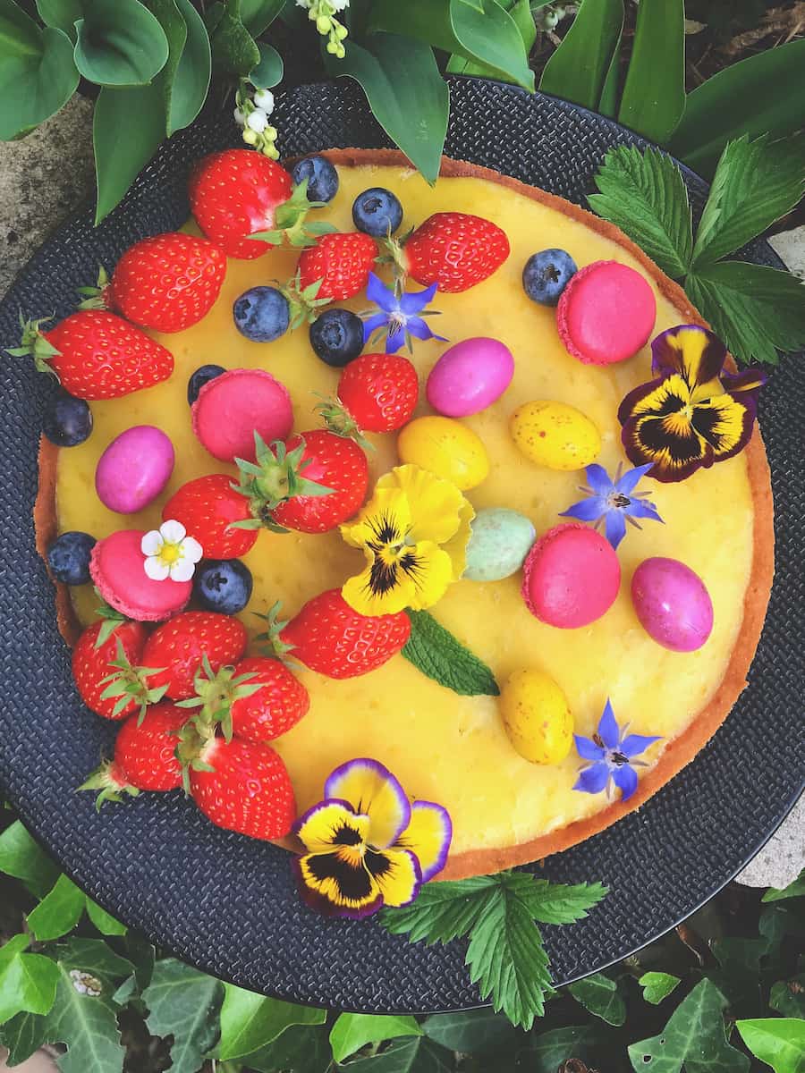 decorated lemon tart with berries and edible flowers