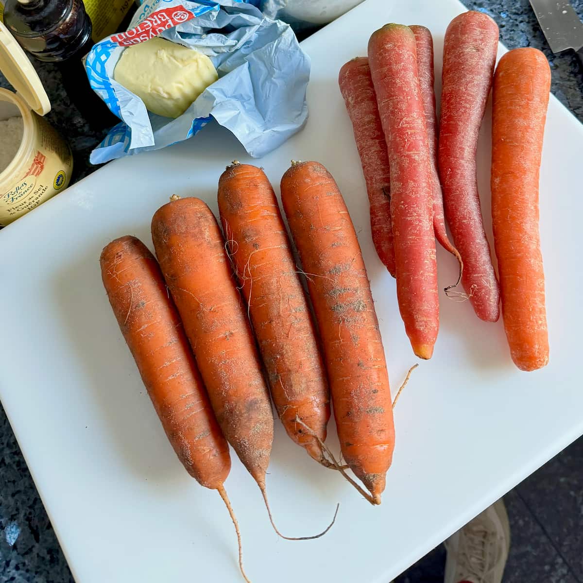 fresh orange carrots covered in sand and some long red carrots