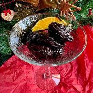 glass dish of prunes soaked in red wine, garnished with orange and spices