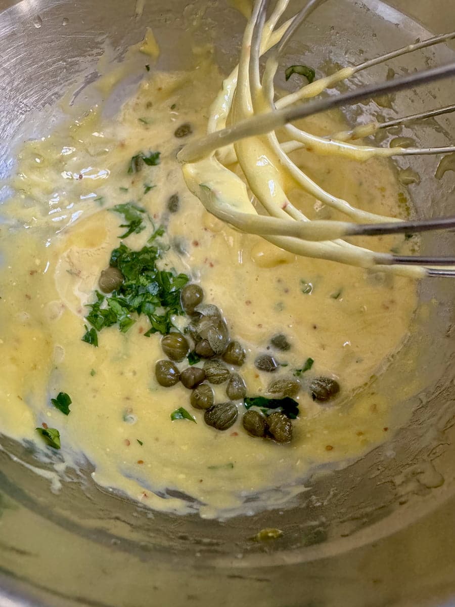 whisking together chopped herbs and capers into mayonnaise to make Tartar sauce