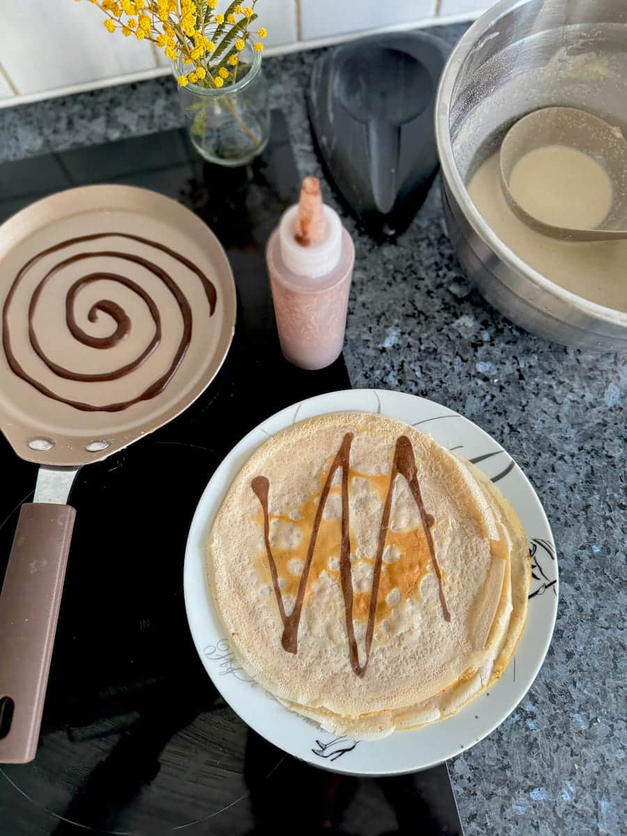 thin French pancakes with chocolate designs like spirals and zigzags using a squeezy bottle