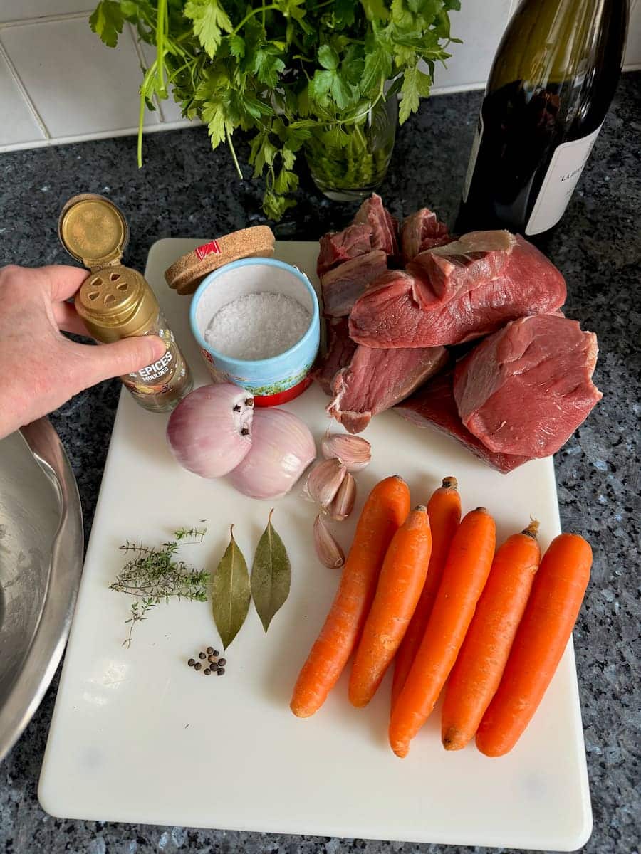 chuck steak, onion, spices, red wine and carrots laid out as marinade ingredient for classic Boeuf Bourguignon