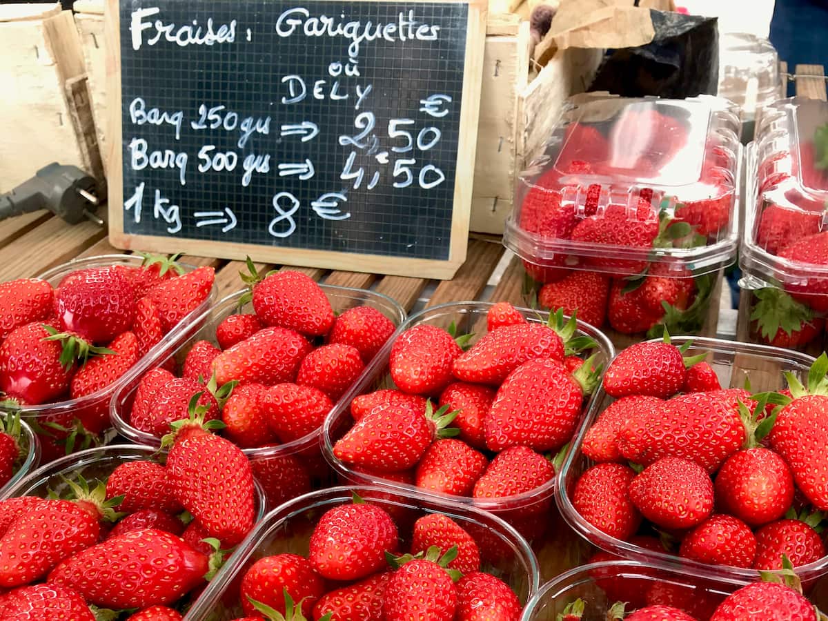 tubs of shiny French gariguette strawberries at the market, long, thin and acidic yet sweet berries