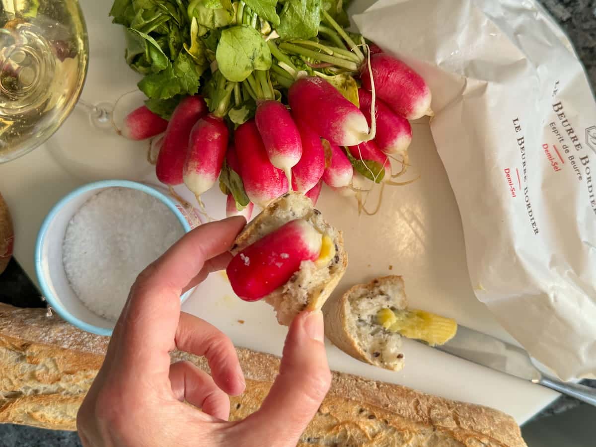 holding a French breakfast radish with butter, salt on a bit of bread