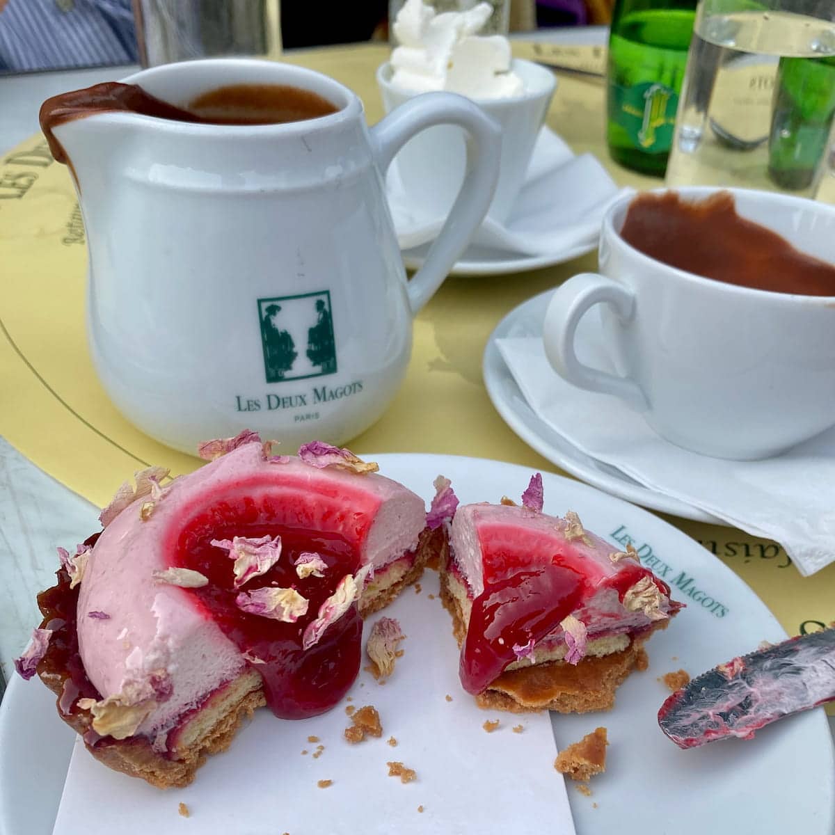 jug of chocolat chaud at les 2 magots in Paris with a raspberry pastry